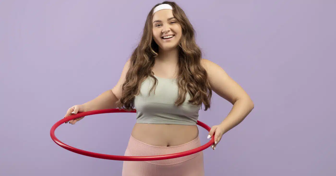 Smiling Young European Plus Size Female In Uniform Doing Exercises With Hula Hoop