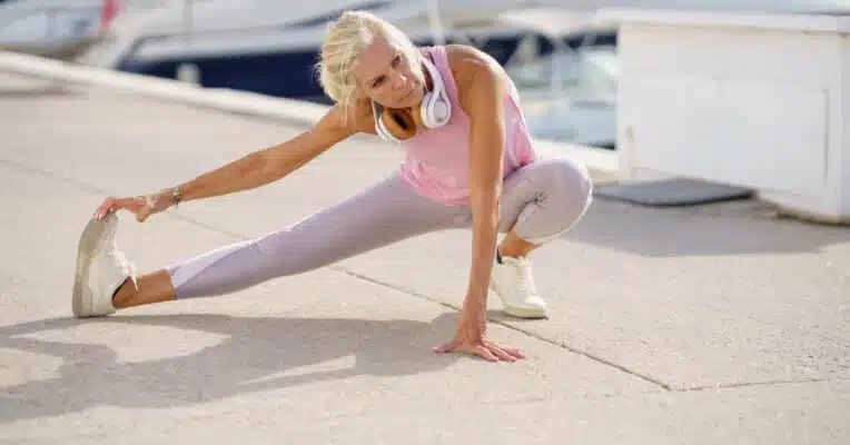 Elderly sportswoman stretching legs during training